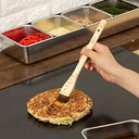 Tare fırçasıyla teppan üzerindeki okonomiyaki ye sos sürülürken — görsel 5